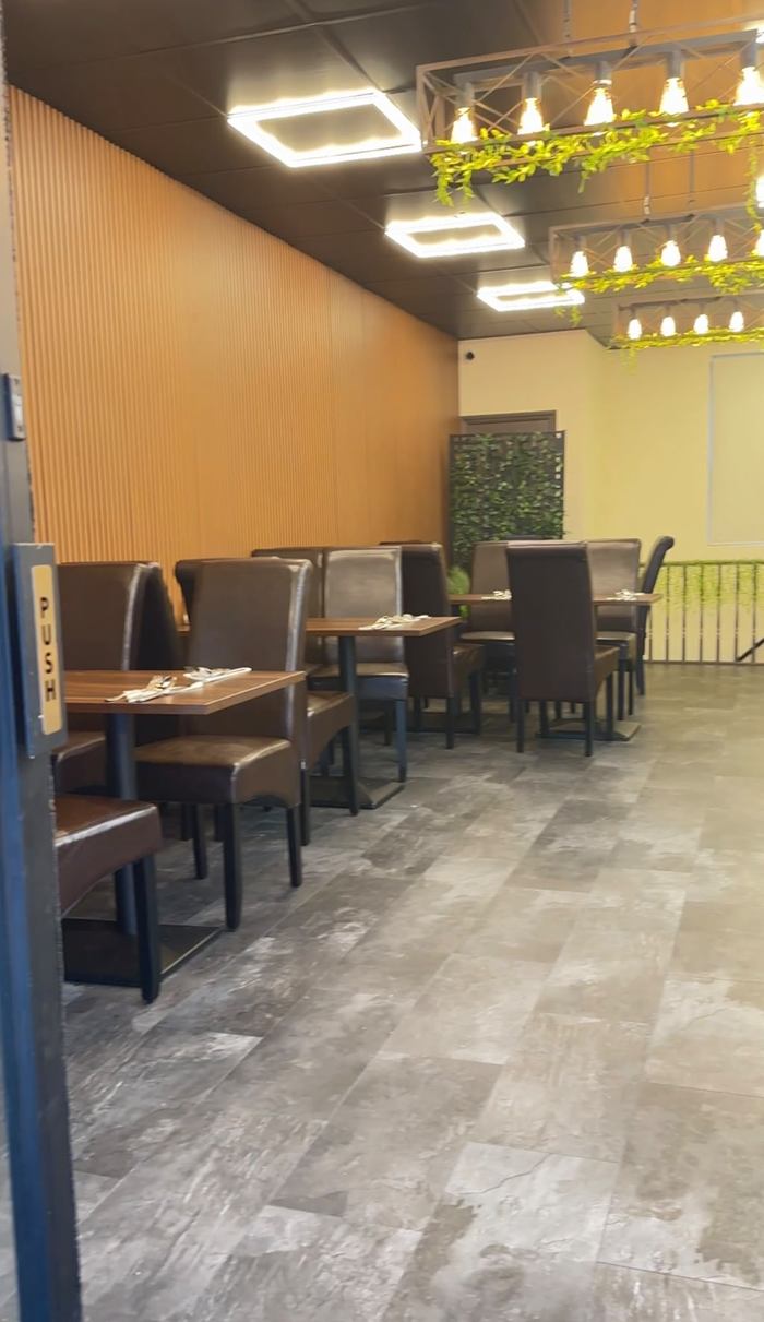 Inside Pasha: wooden tables, brown leather chairs and hanging lights with greenery